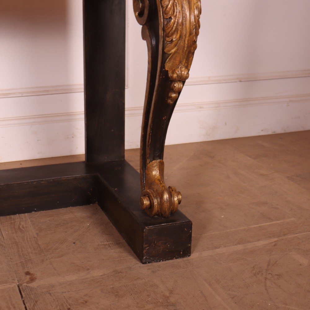 A dark painted and parcel-gilt console table featuring carved acanthus leaf scroll front supports and a flat plinth base. View IV