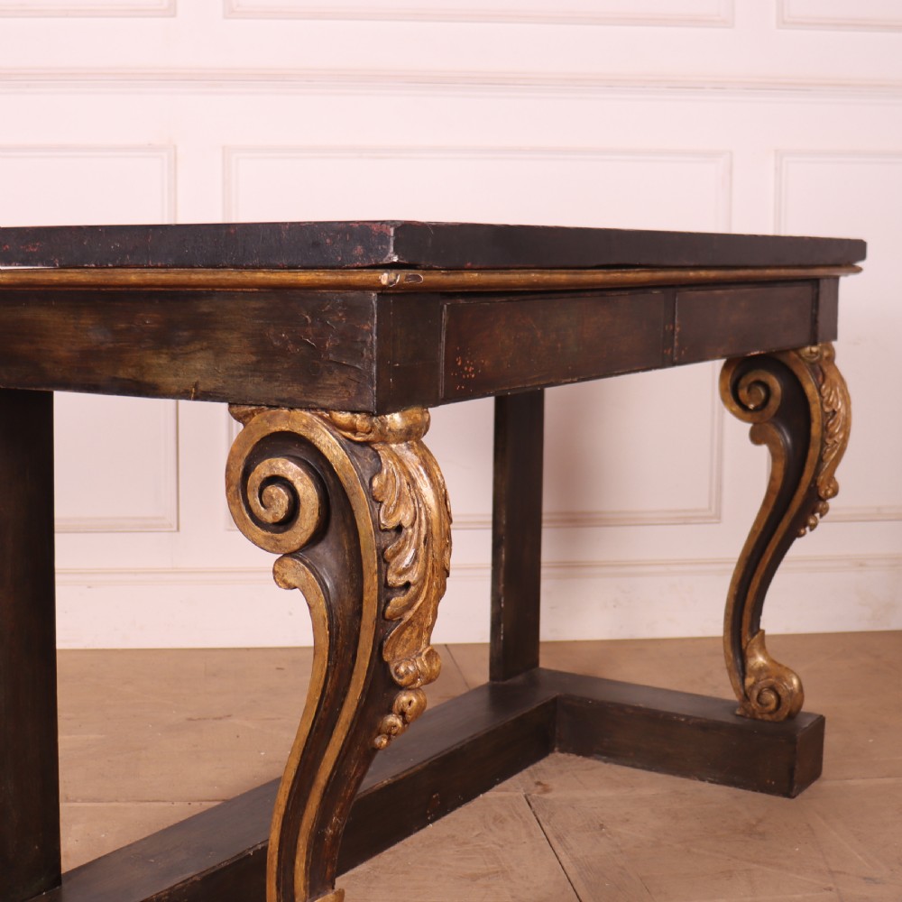 A dark painted and parcel-gilt console table featuring carved acanthus leaf scroll front supports and a flat plinth base. View VII