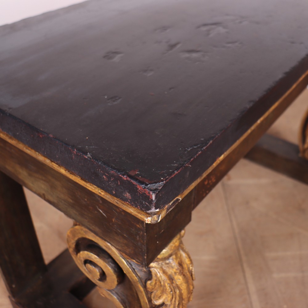 A dark painted and parcel-gilt console table featuring carved acanthus leaf scroll front supports and a flat plinth base. View VIII
