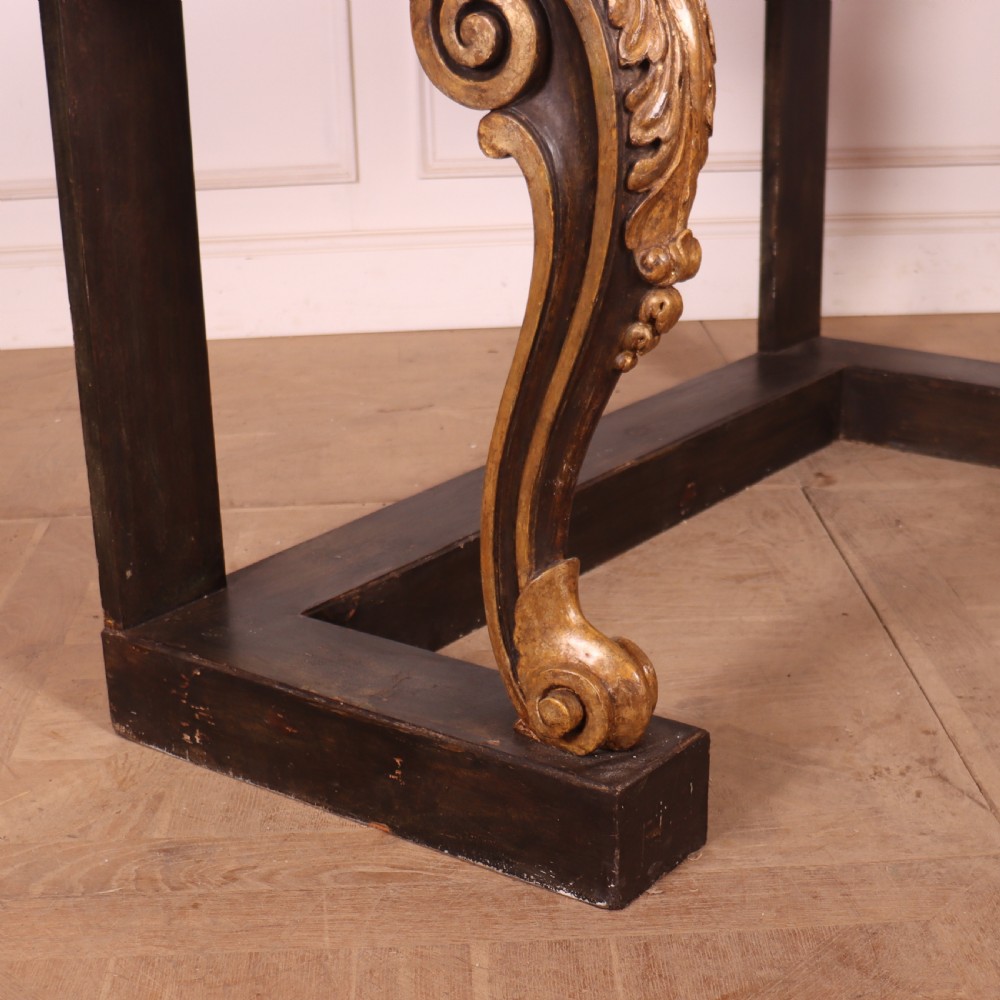 A dark painted and parcel-gilt console table featuring carved acanthus leaf scroll front supports and a flat plinth base. View IX