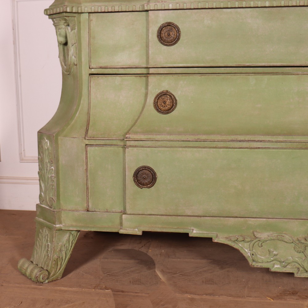 A large sage green painted Dutch linen cupboard featuring a broken pediment cornice, carved swag door panels, brass drop handles, and three lower drawers. View II