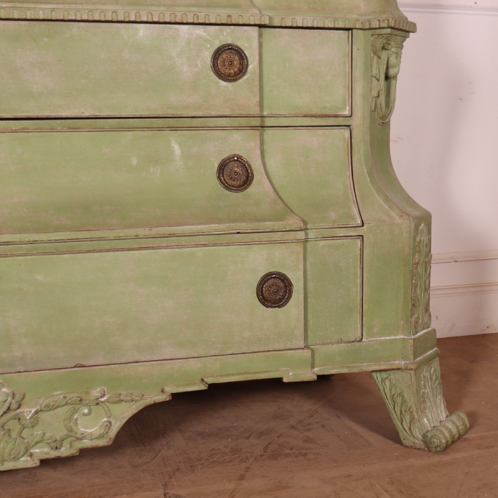 A large sage green painted Dutch linen cupboard featuring a broken pediment cornice, carved swag door panels, brass drop handles, and three lower drawers. View III