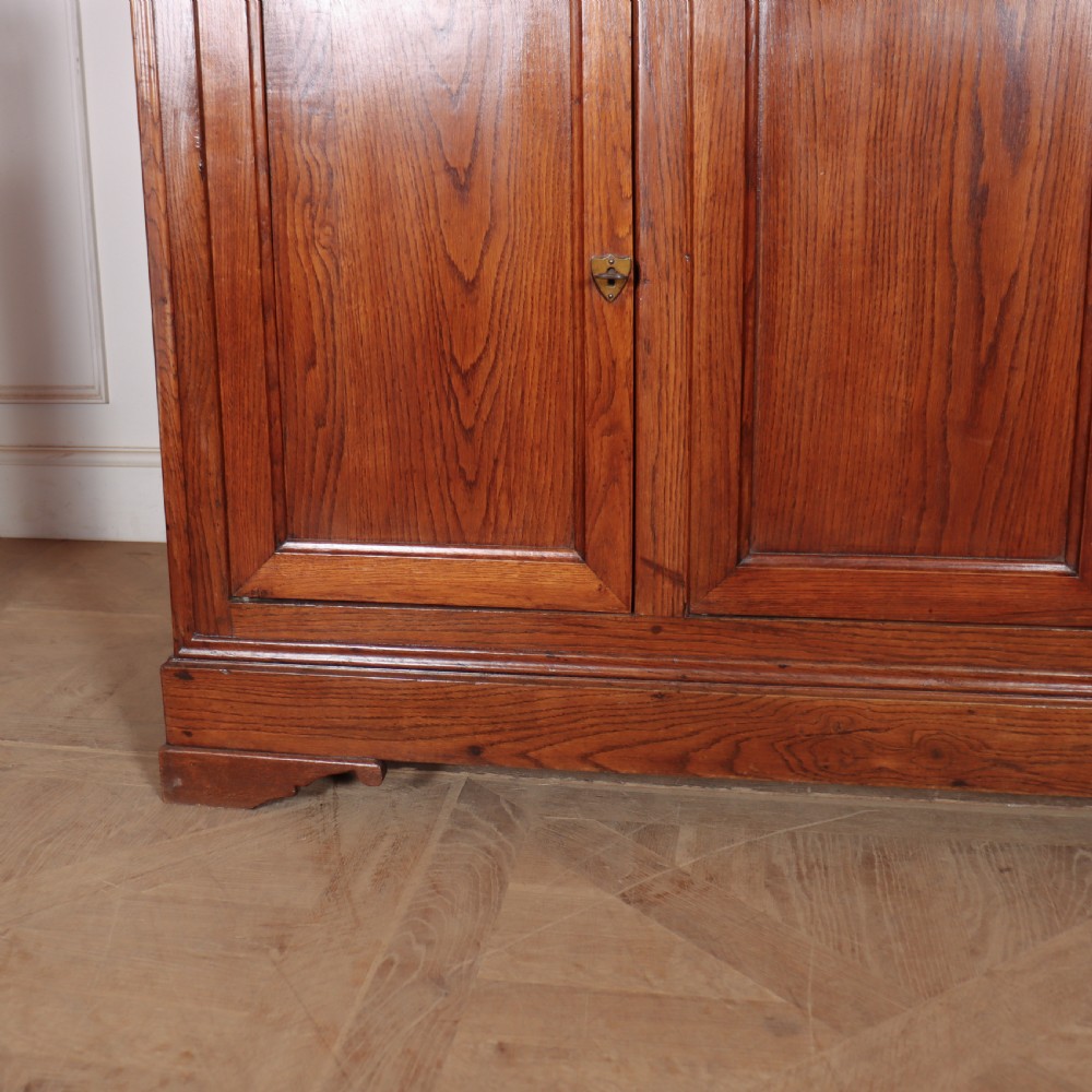 A long French oak enfilade sideboard featuring four field-panel cupboard doors, upper drawers, and central brass key escutcheons. View III