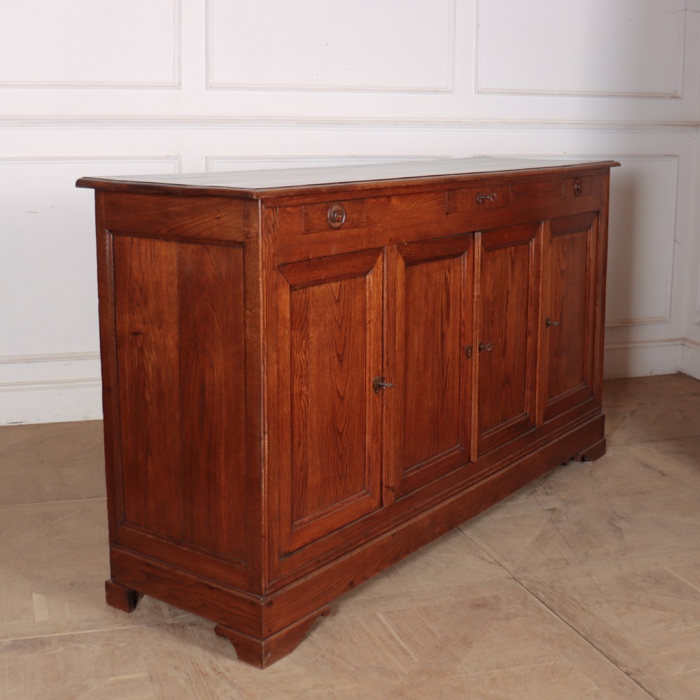 A long French oak enfilade sideboard featuring four field-panel cupboard doors, upper drawers, and central brass key escutcheons. View VII
