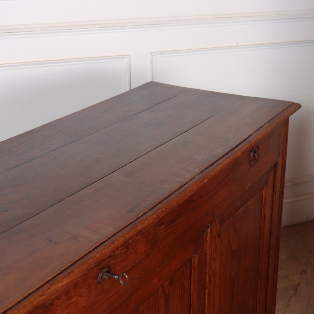 A long French oak enfilade sideboard featuring four field-panel cupboard doors, upper drawers, and central brass key escutcheons. View X