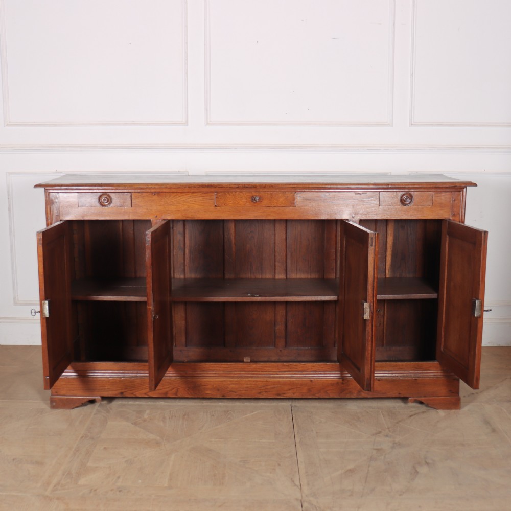 A long French oak enfilade sideboard featuring four field-panel cupboard doors, upper drawers, and central brass key escutcheons. View XI