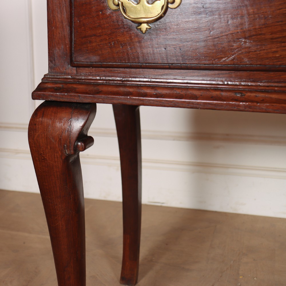 An antique dark oak dresser base featuring three drawers with brass handles and keyhole escutcheons supported on cabriole legs. View III