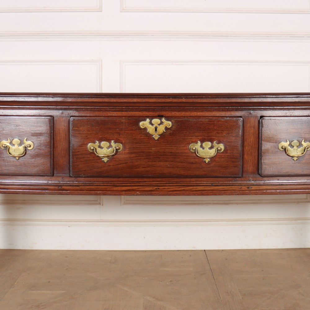An antique dark oak dresser base featuring three drawers with brass handles and keyhole escutcheons supported on cabriole legs. View IV