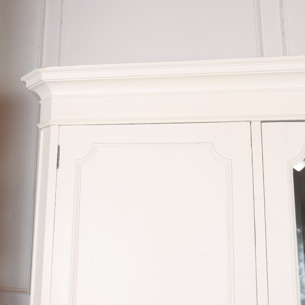 A large 19th-century off-white painted wardrobe featuring three doors, a central arched full-length mirror, moulded cornice, and drop handles. View III
