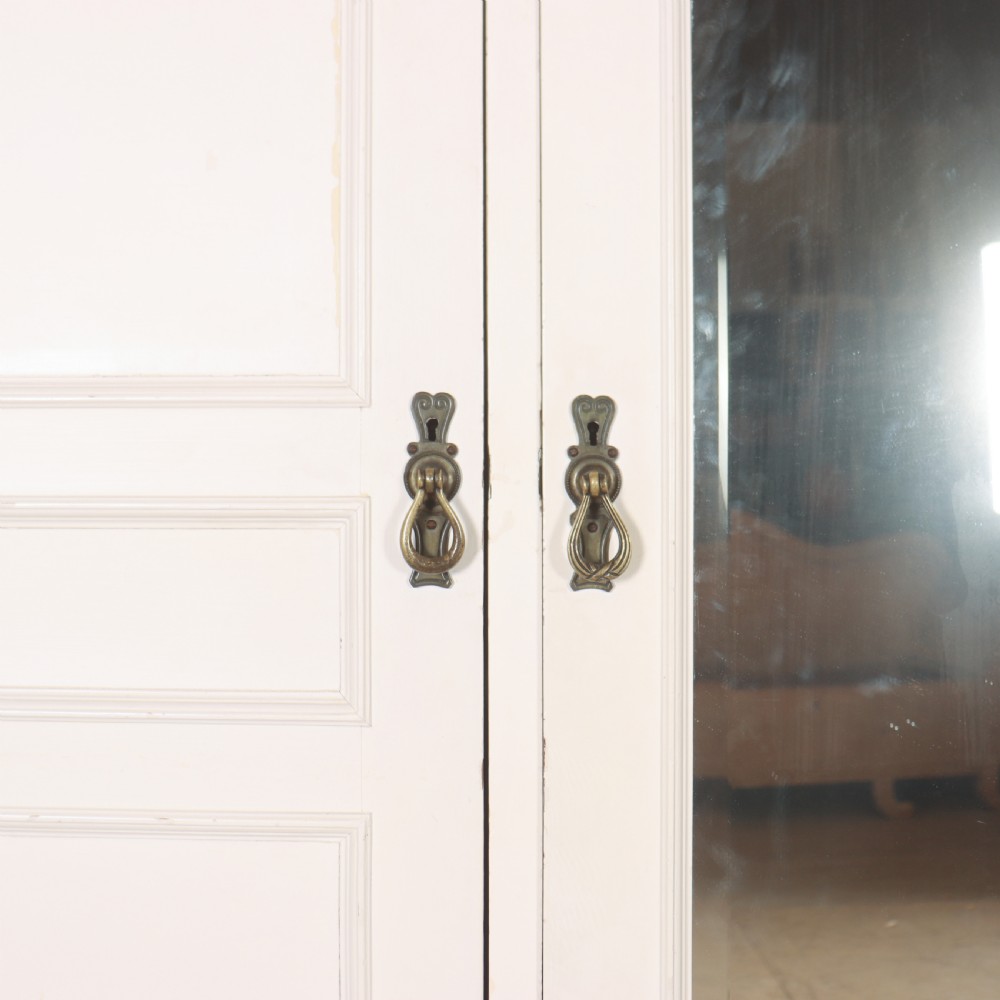 A large 19th-century off-white painted wardrobe featuring three doors, a central arched full-length mirror, moulded cornice, and drop handles. View V