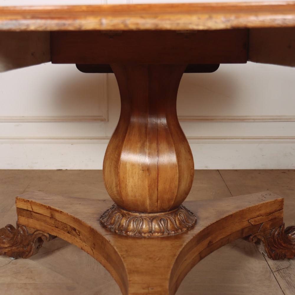 A large 19th-century circular wood supper table featuring a bulbous turned pedestal column and carved paw feet on a triform base. View VII