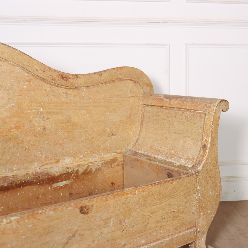 A Swedish wooden storage bench featuring a contoured backrest, rolled armrests, and an open seat box with distressed yellow paint finish. View III
