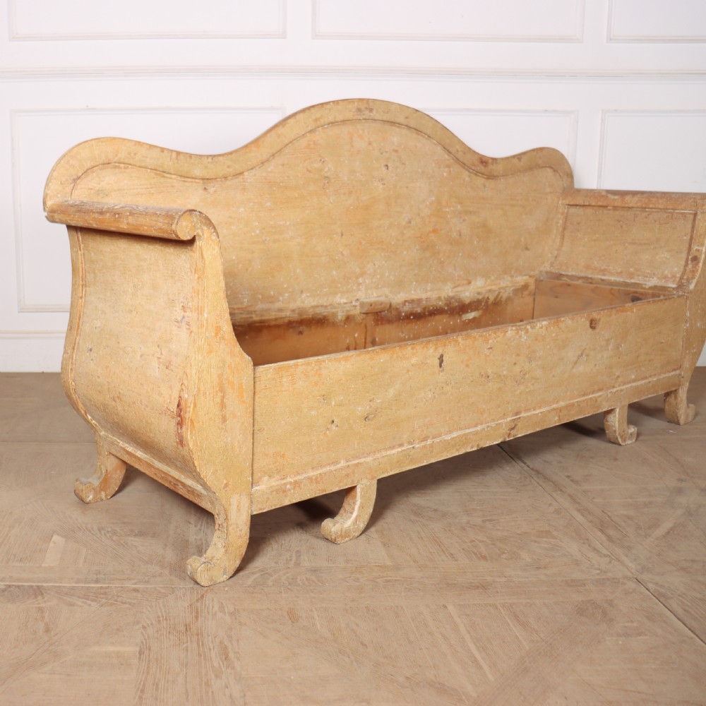 A Swedish wooden storage bench featuring a contoured backrest, rolled armrests, and an open seat box with distressed yellow paint finish. View II