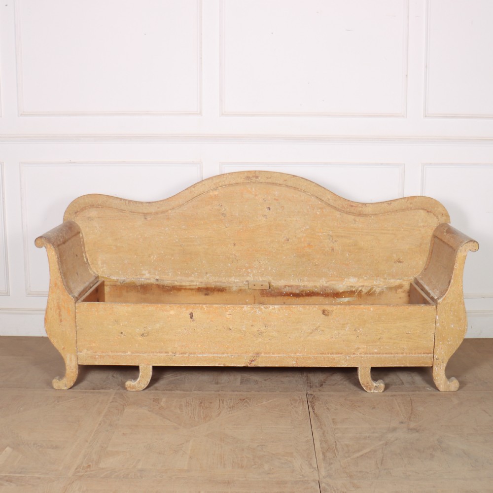 A Swedish wooden storage bench featuring a contoured backrest, rolled armrests, and an open seat box with distressed yellow paint finish. View IV
