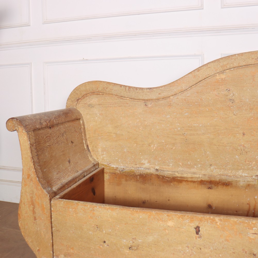 A Swedish wooden storage bench featuring a contoured backrest, rolled armrests, and an open seat box with distressed yellow paint finish. View V