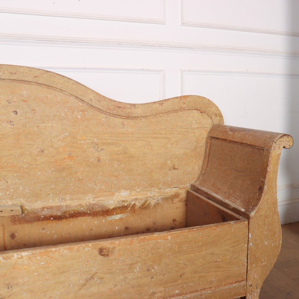 A Swedish wooden storage bench featuring a contoured backrest, rolled armrests, and an open seat box with distressed yellow paint finish. View VI