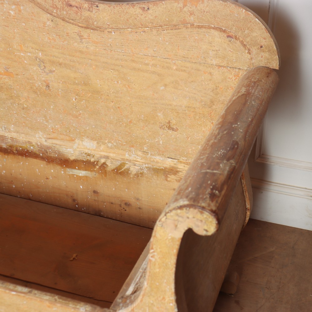 A Swedish wooden storage bench featuring a contoured backrest, rolled armrests, and an open seat box with distressed yellow paint finish. View VII