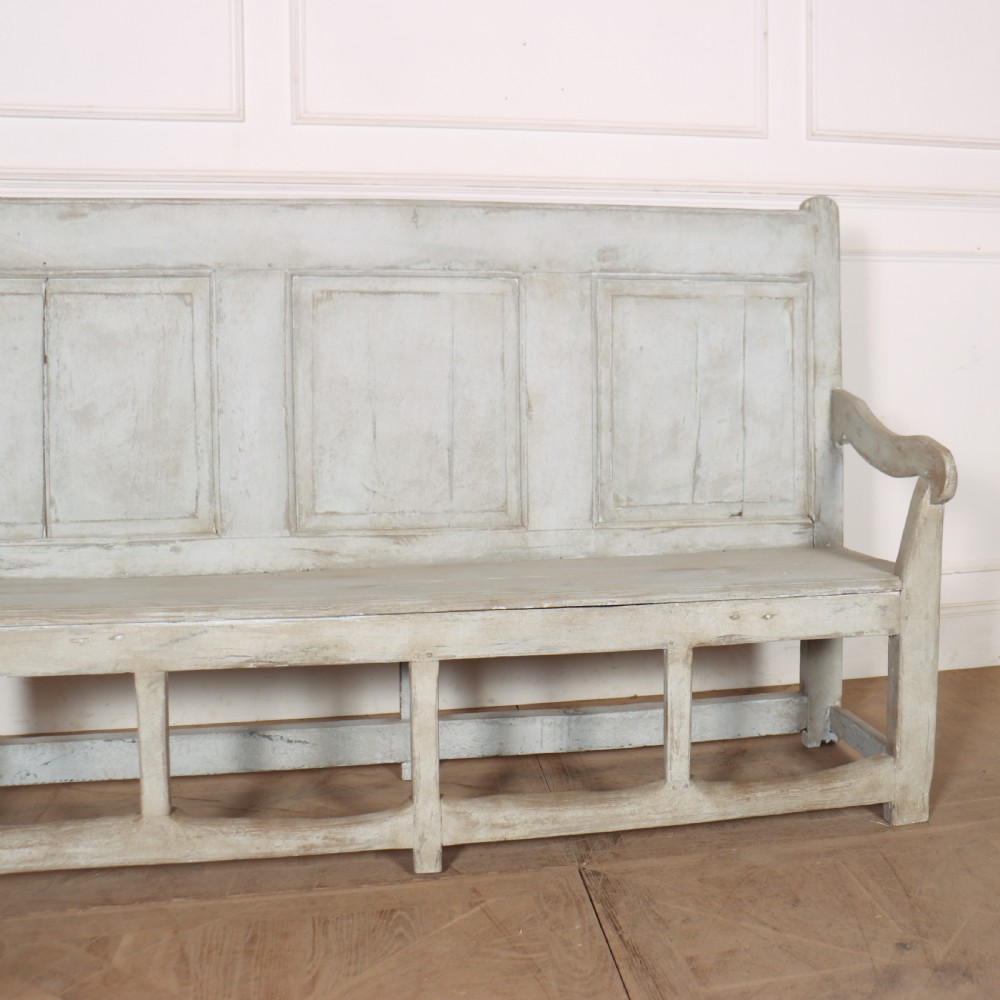 An 18th-century painted wooden tavern bench featuring a high back with three recessed panels, curved armrests, and lower stretchers. View III