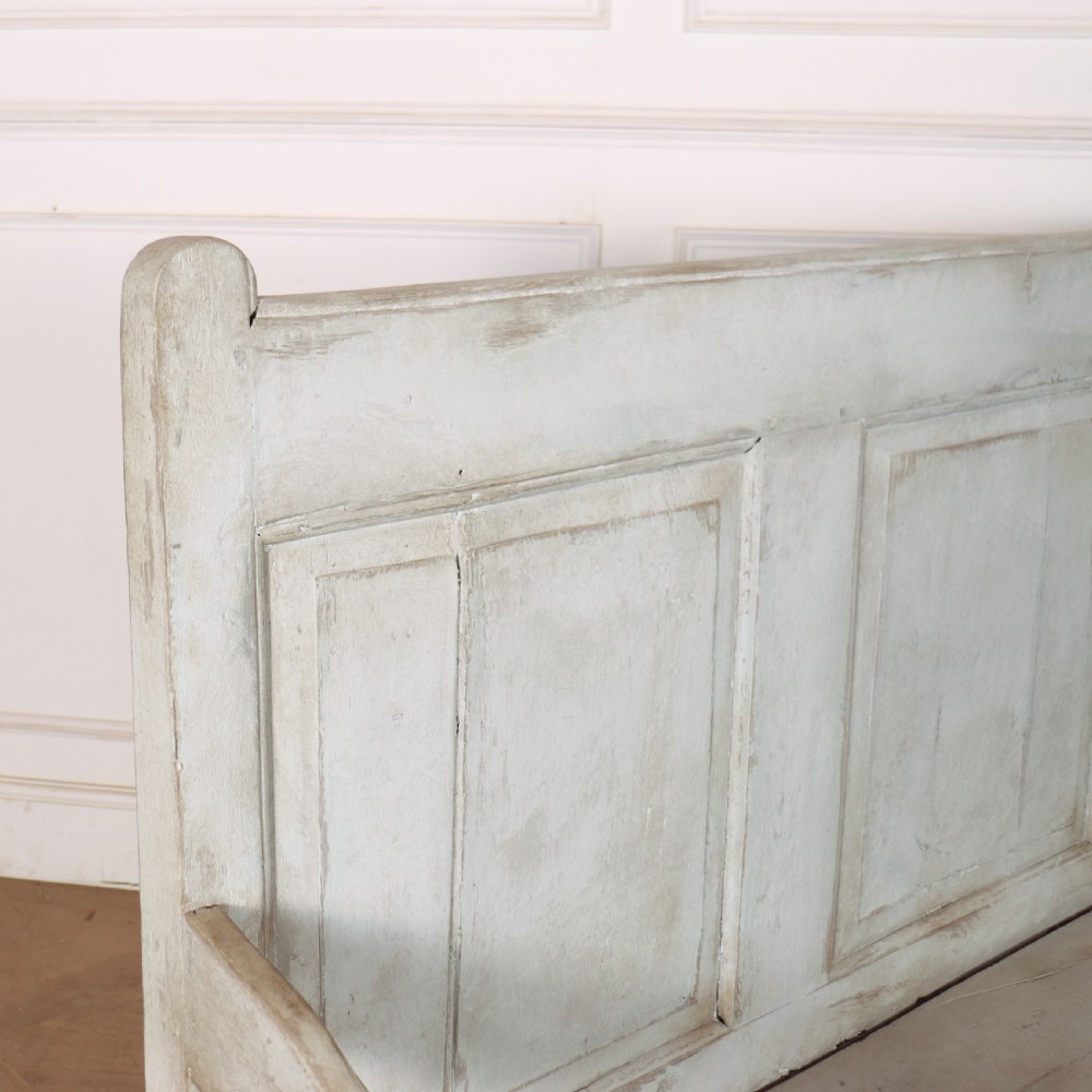 An 18th-century painted wooden tavern bench featuring a high back with three recessed panels, curved armrests, and lower stretchers. View IX
