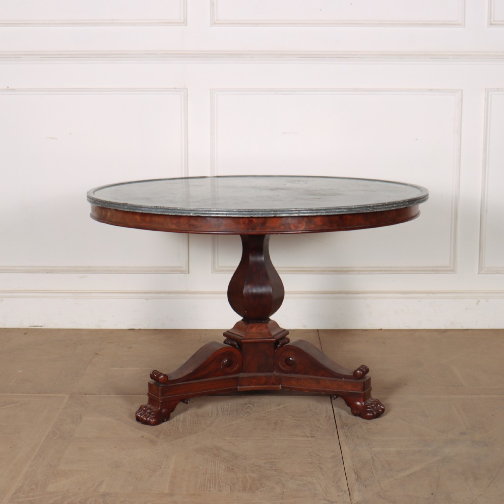 A large circular French gueridon table featuring a dark grey marble top set upon a dark mahogany pedestal base with a triform platform and carved paw feet. View II