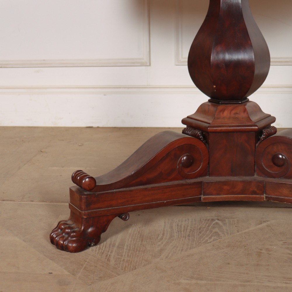 A large circular French gueridon table featuring a dark grey marble top set upon a dark mahogany pedestal base with a triform platform and carved paw feet. View III