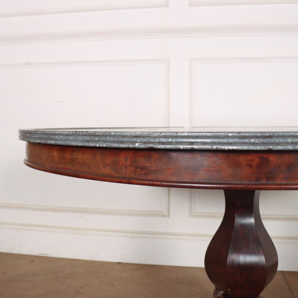 A large circular French gueridon table featuring a dark grey marble top set upon a dark mahogany pedestal base with a triform platform and carved paw feet. View VI