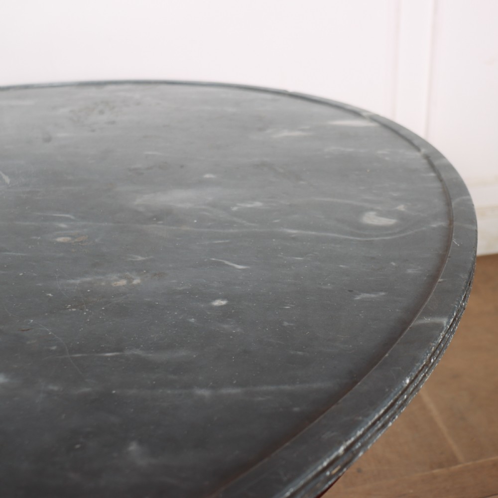 A large circular French gueridon table featuring a dark grey marble top set upon a dark mahogany pedestal base with a triform platform and carved paw feet. View VIII