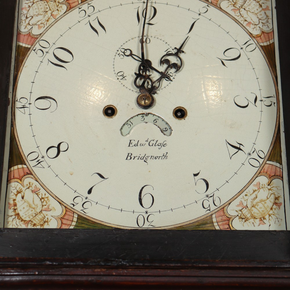 An antique dark brown wooden housekeepers cupboard featuring panelled doors, a central integrated grandfather clock, and a base section with six drawers. View VIII