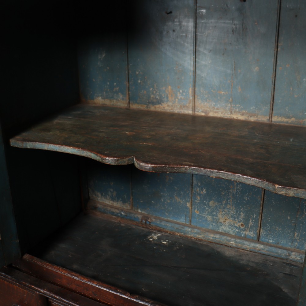 An antique dark brown wooden housekeepers cupboard featuring panelled doors, a central integrated grandfather clock, and a base section with six drawers. View XI
