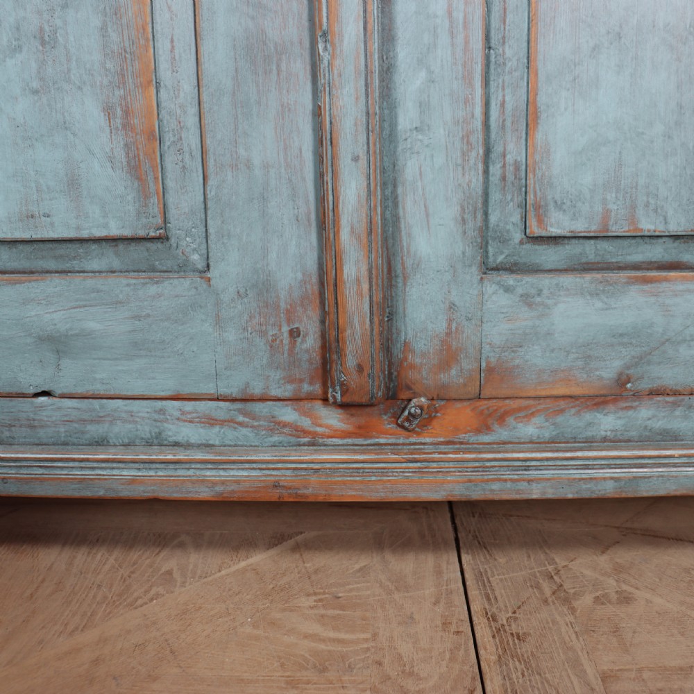 A freestanding Swedish blue painted wooden cupboard featuring two panelled doors, dentil moulding at the cornice, and short tapered feet. View V