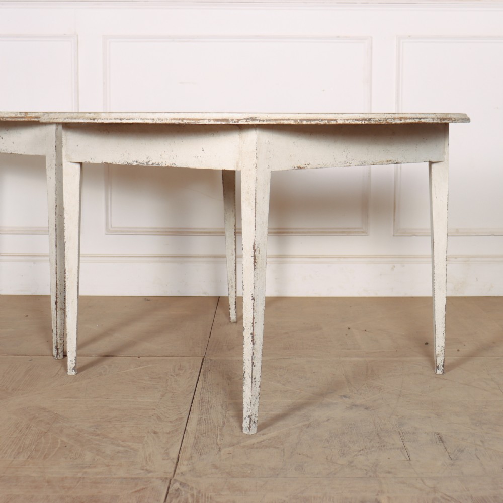 A pair of Swedish demi-lune console tables with distressed off-white painted finish and tapered legs. View II