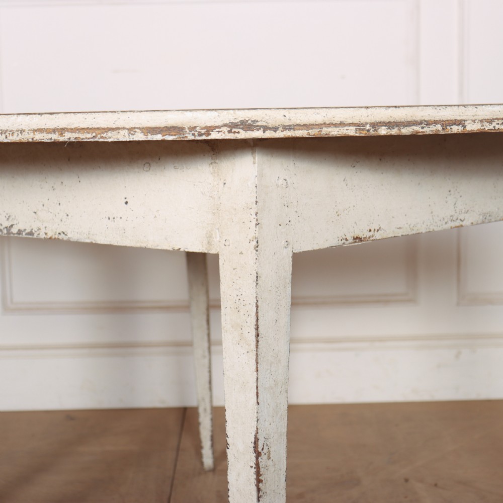 A pair of Swedish demi-lune console tables with distressed off-white painted finish and tapered legs. View III