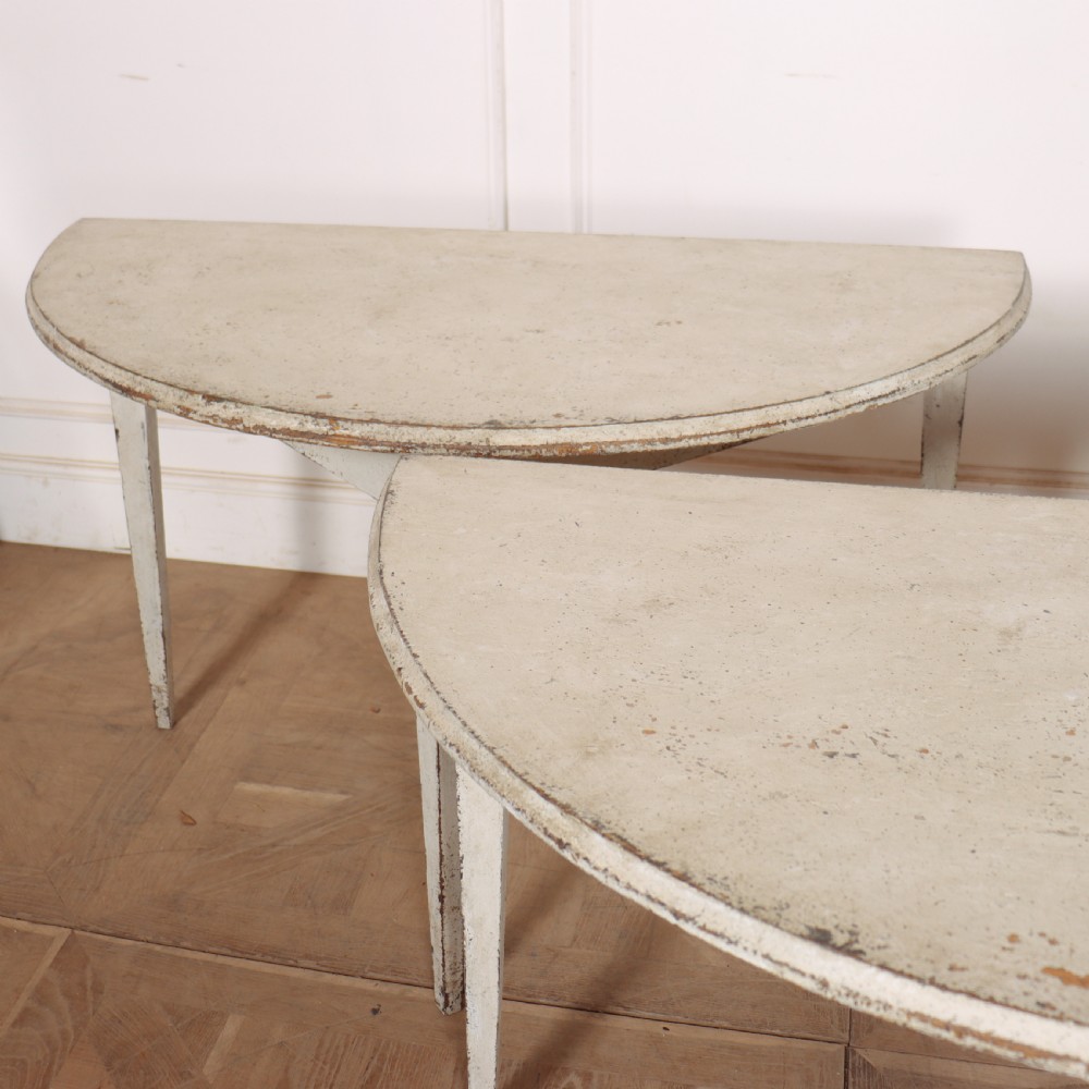 A pair of Swedish demi-lune console tables with distressed off-white painted finish and tapered legs. View IV