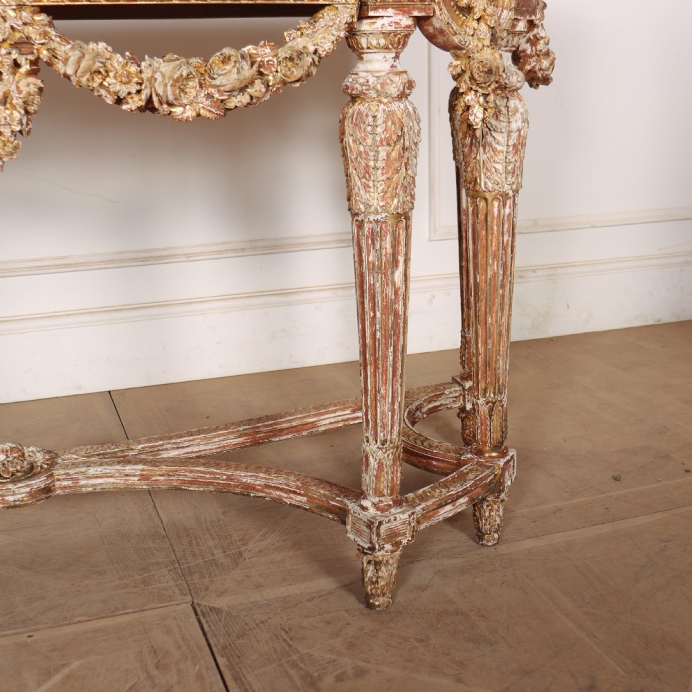 A 19th-century French demi-lune console table featuring a green marble top, ornate carved giltwood frieze with floral swags, and fluted legs. View V