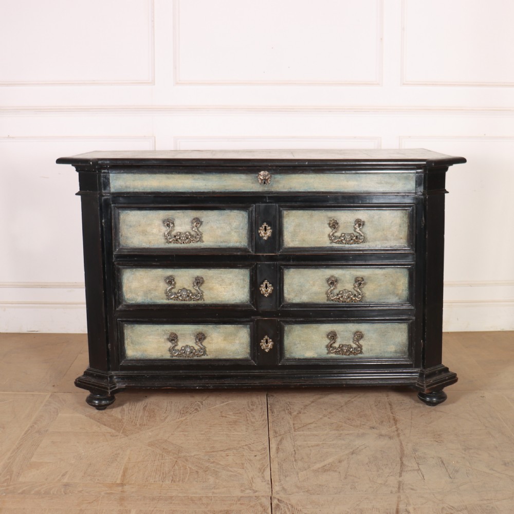 An 18th-century Italian three-drawer commode with a black painted frame, pale blue drawer panels, ornate brass handles, and bun feet.
