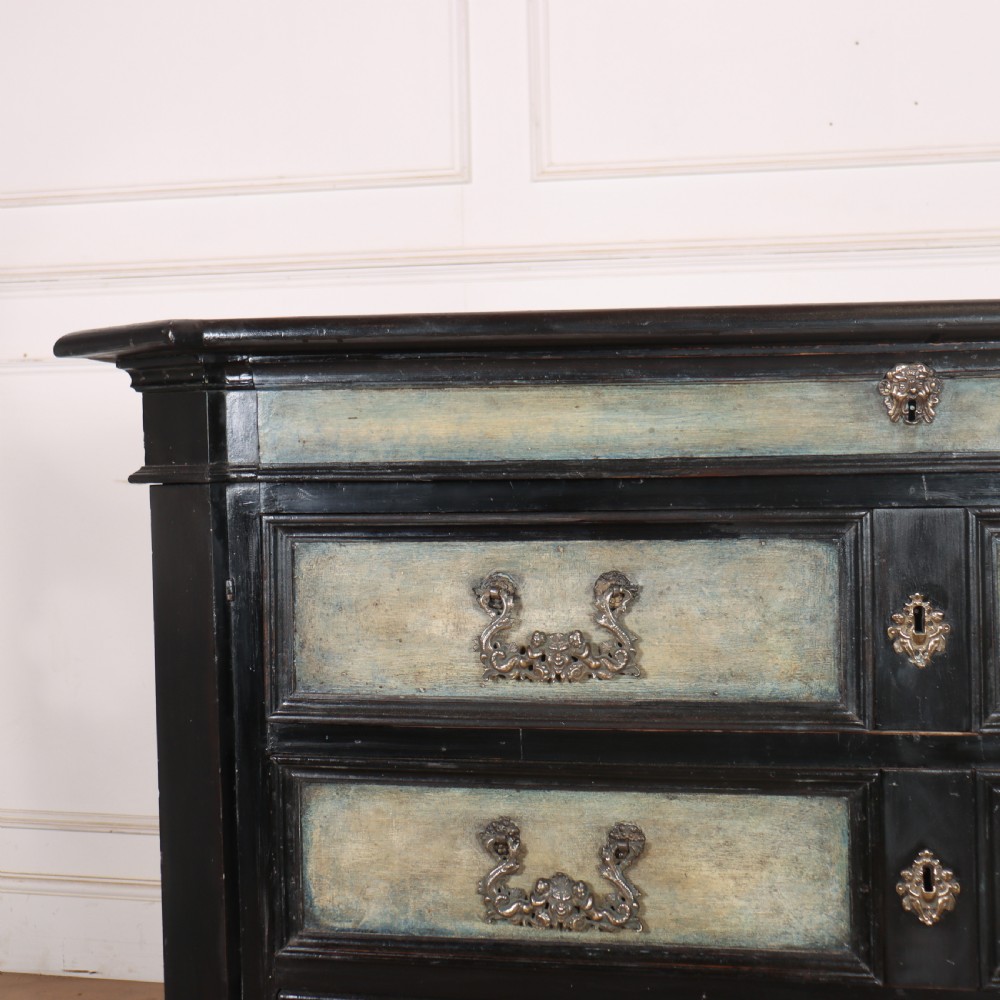 An 18th-century Italian three-drawer commode with a black painted frame, pale blue drawer panels, ornate brass handles, and bun feet. View V