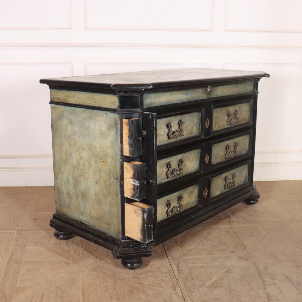 An 18th-century Italian three-drawer commode with a black painted frame, pale blue drawer panels, ornate brass handles, and bun feet. View X