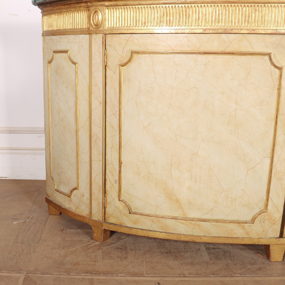 A Neoclassical style cream painted demi-lune side cabinet featuring a dark green marble top, fluted gilded frieze, and panelled cupboard doors. View II