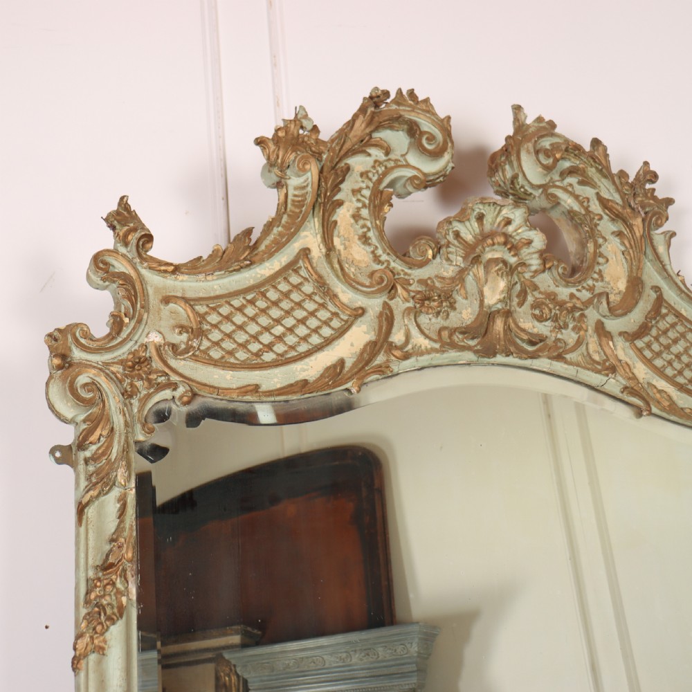 A tall French Rococo style mirror featuring an arched frame painted in pale grey-green with carved giltwood C-scrolls, lattice work, and foliate garlands. View II