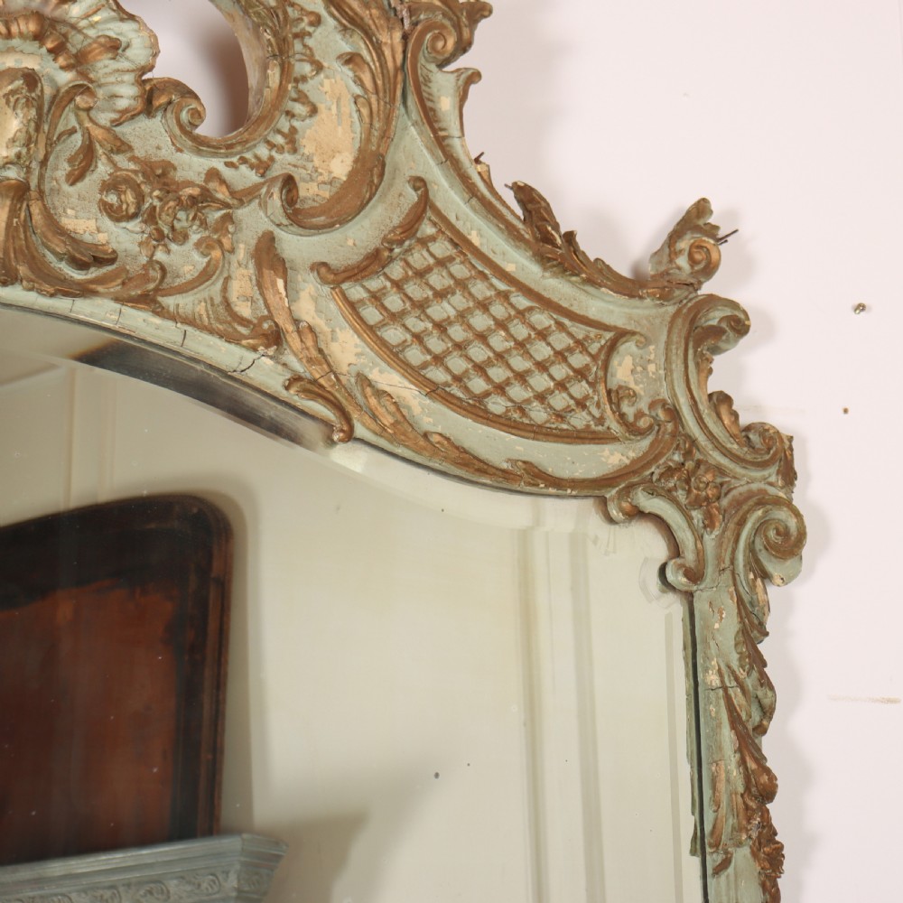 A tall French Rococo style mirror featuring an arched frame painted in pale grey-green with carved giltwood C-scrolls, lattice work, and foliate garlands. View III