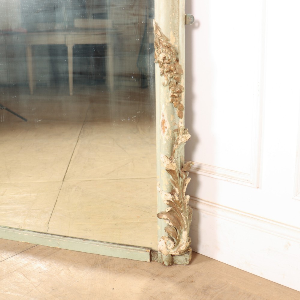 A tall French Rococo style mirror featuring an arched frame painted in pale grey-green with carved giltwood C-scrolls, lattice work, and foliate garlands. View VII