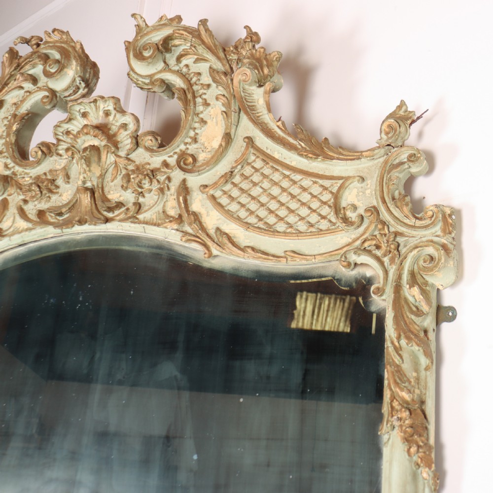 A tall French Rococo style mirror featuring an arched frame painted in pale grey-green with carved giltwood C-scrolls, lattice work, and foliate garlands. View VIII
