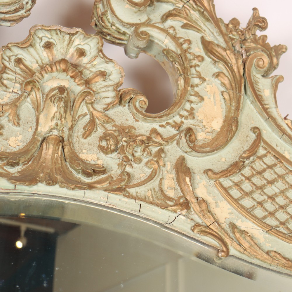 A tall French Rococo style mirror featuring an arched frame painted in pale grey-green with carved giltwood C-scrolls, lattice work, and foliate garlands. View X