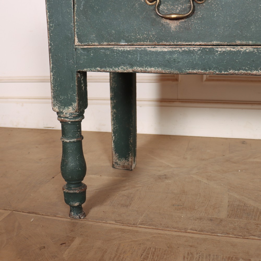 An English wooden dresser base painted in distressed muted green with three drawers and brass swan-neck handles. View VI