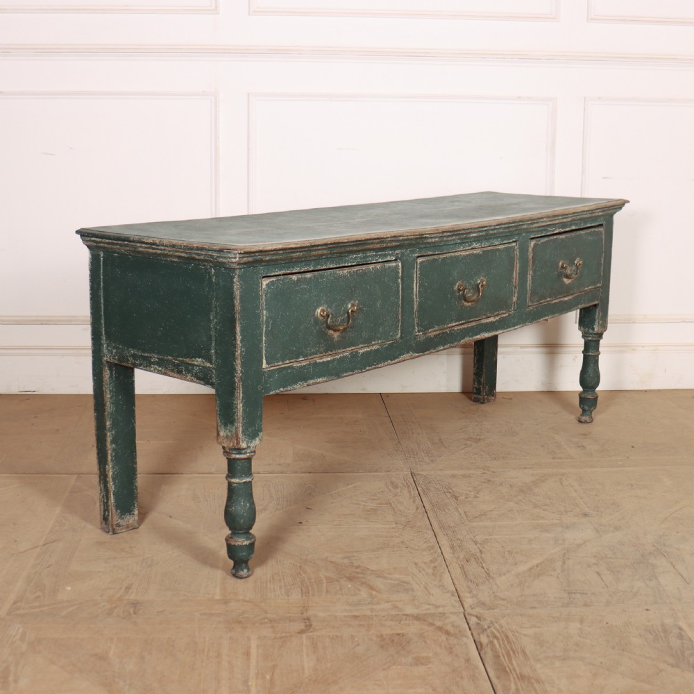 An English wooden dresser base painted in distressed muted green with three drawers and brass swan-neck handles. View VIII