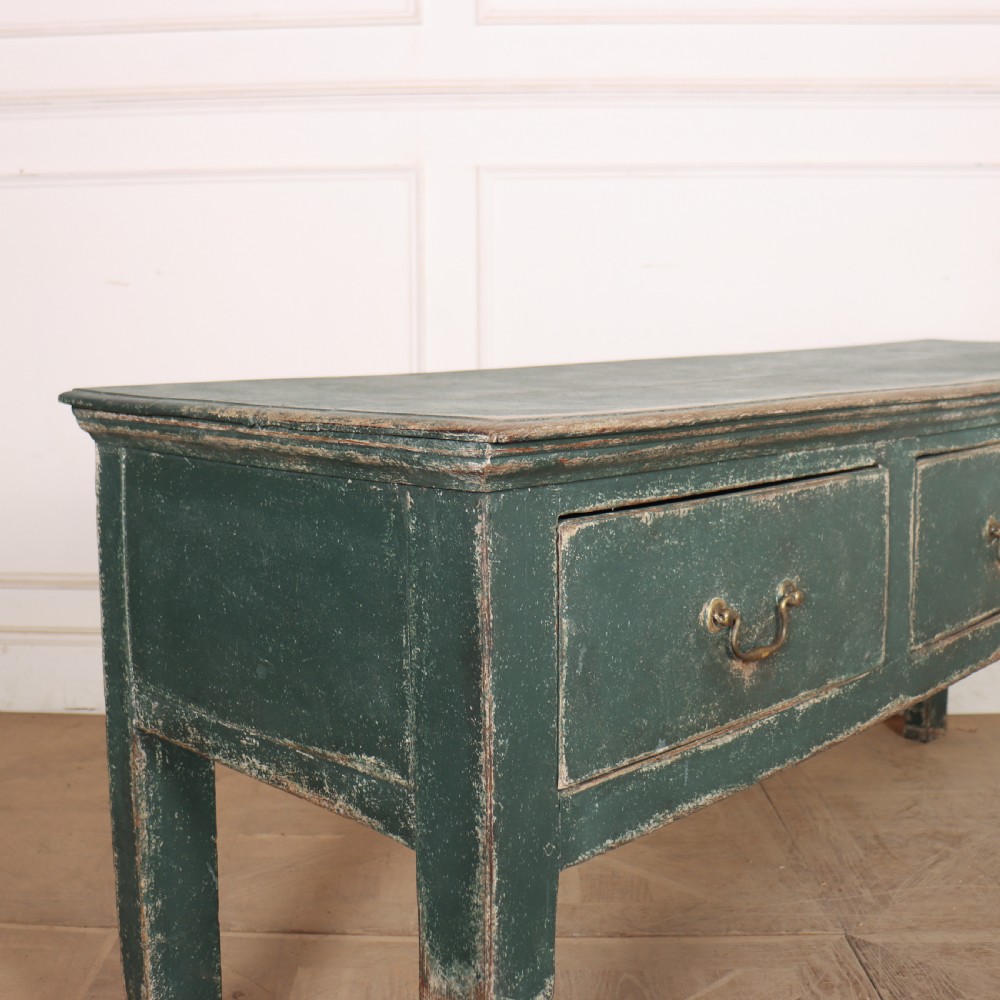 An English wooden dresser base painted in distressed muted green with three drawers and brass swan-neck handles. View IX