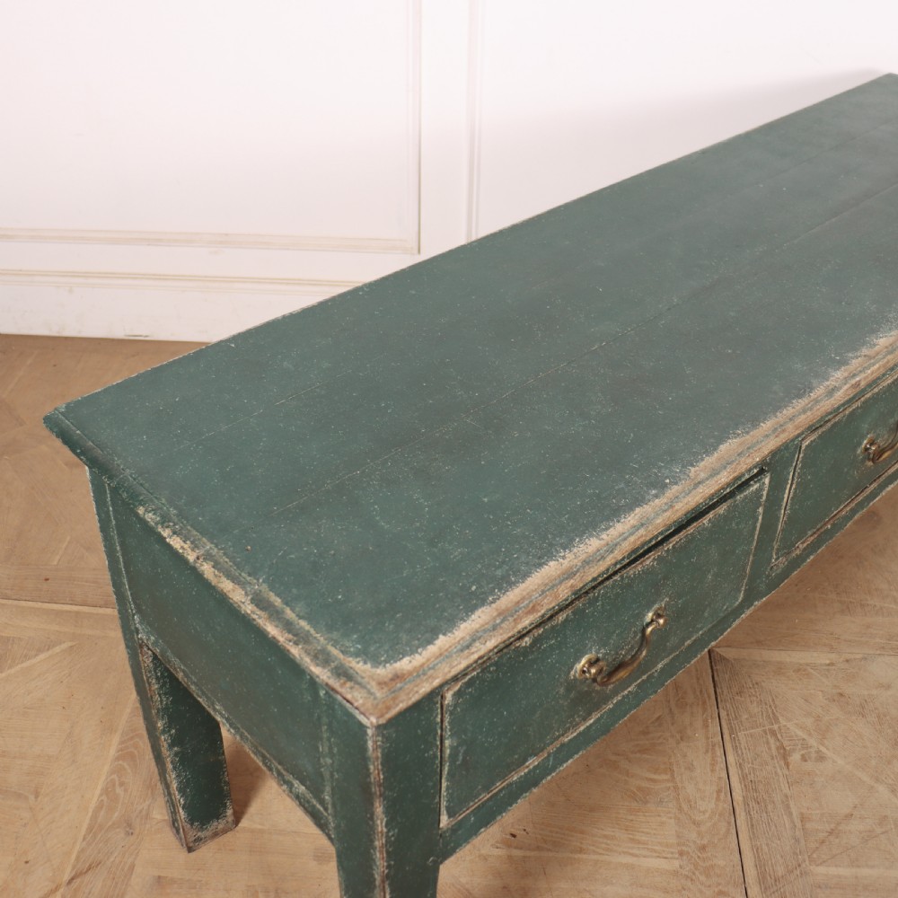 An English wooden dresser base painted in distressed muted green with three drawers and brass swan-neck handles. View XI