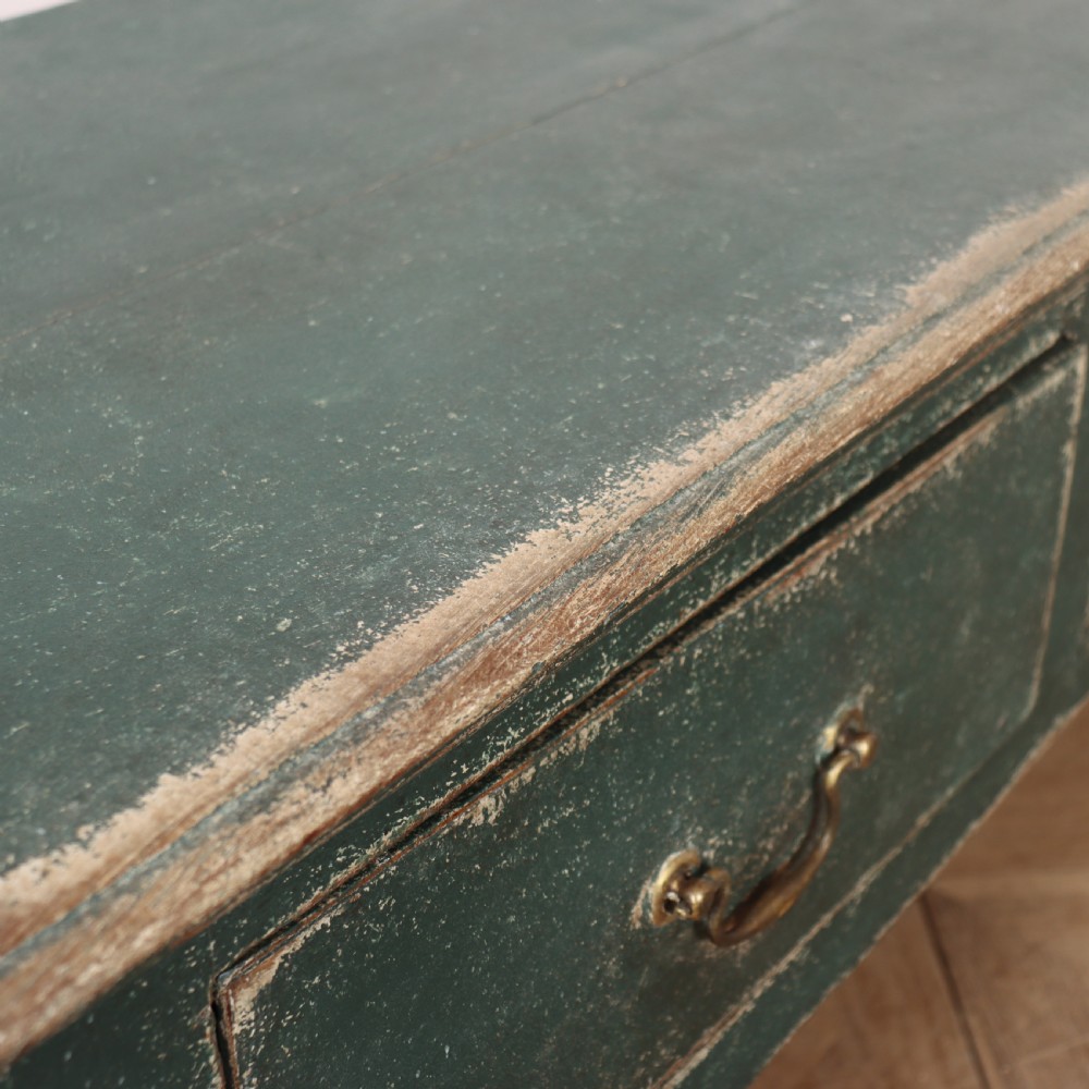 An English wooden dresser base painted in distressed muted green with three drawers and brass swan-neck handles. View XII