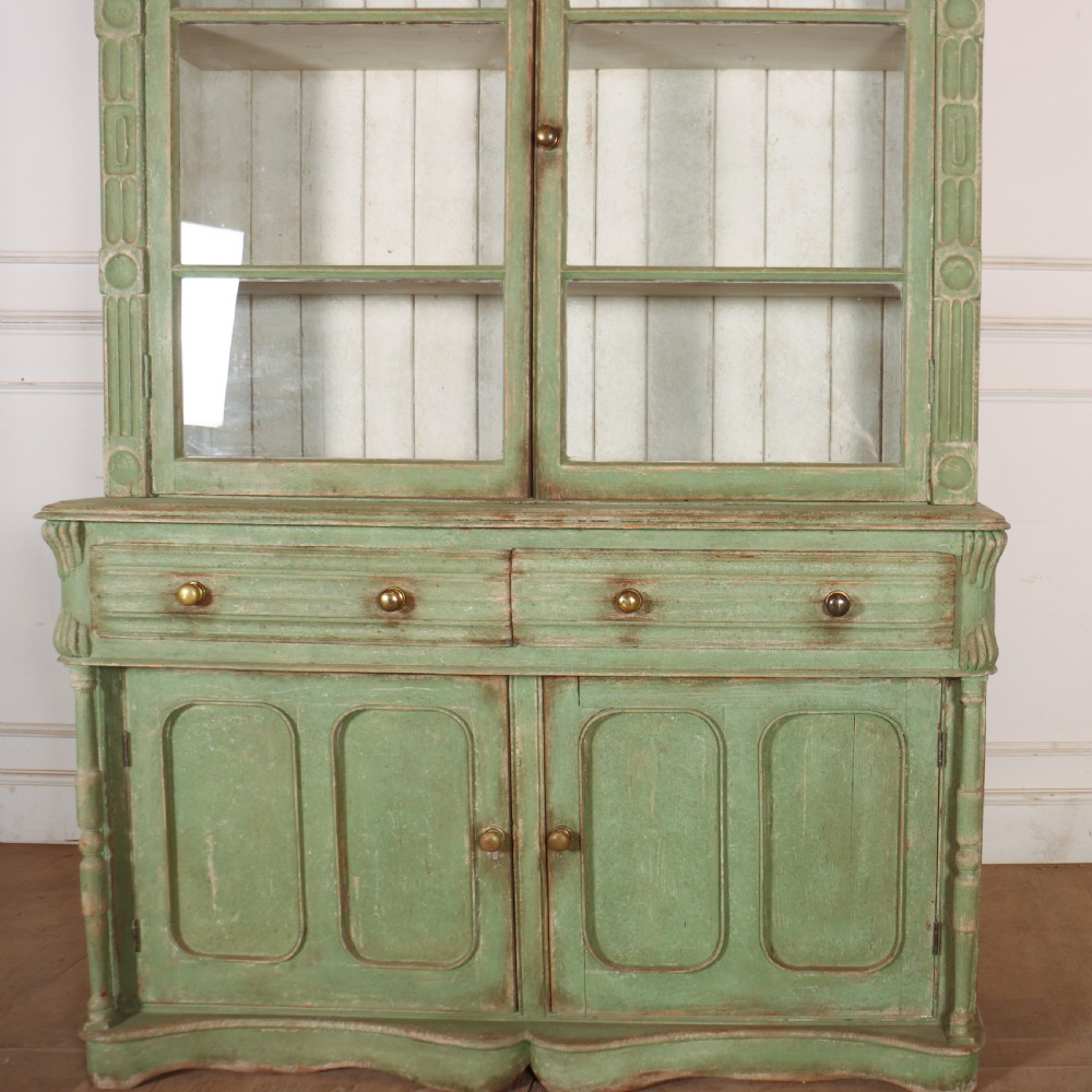 An antique West Country kitchen dresser in distressed sage green paint, featuring upper glazed doors and lower panelled cupboards. View II