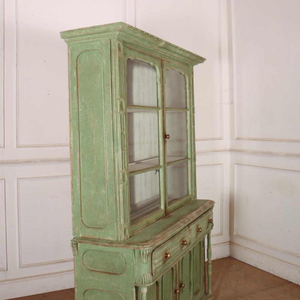 An antique West Country kitchen dresser in distressed sage green paint, featuring upper glazed doors and lower panelled cupboards. View IX